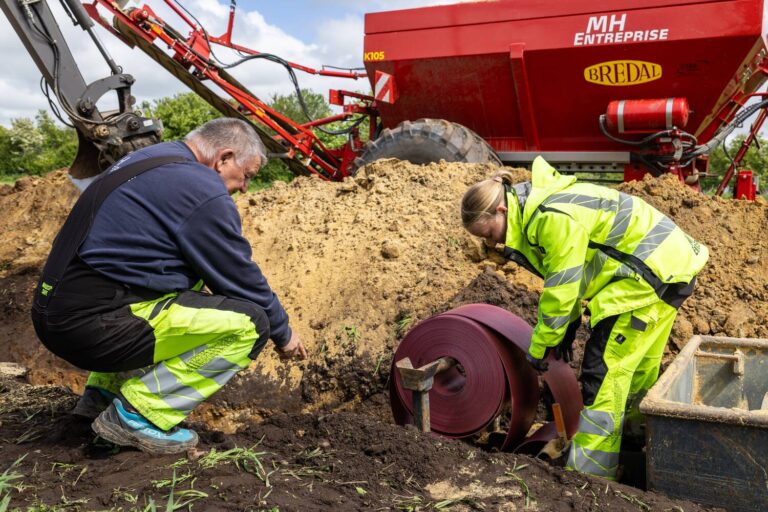 To arbejdere installerer kabeltromle ved landbrugsmaskine