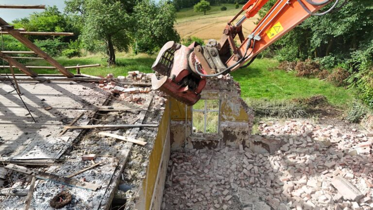 Gravemaskine river mur ned ved husnedrivning